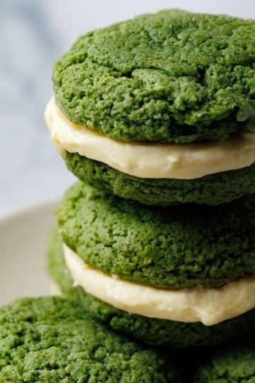 Stack of green whoopie pies with cream cheese filling on a white plate