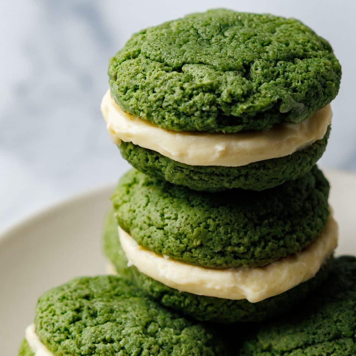 Stack of green whoopie pies with cream cheese filling on a white plate