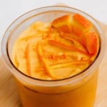 Creamy orange protein ice cream in Ninja Creami pint with orange slices on top viewed from above