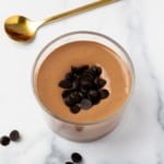Creamy cottage cheese chocolate pudding topped with dark chocolate chips in a small jar on marble.