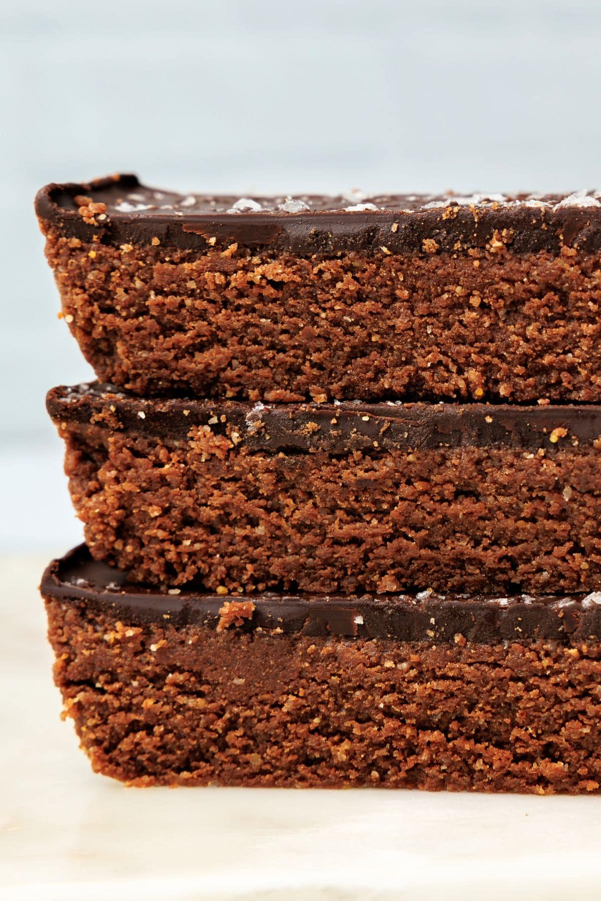 Close side view of stacked chocolate protein bars with a dense crumb and glossy chocolate coating.