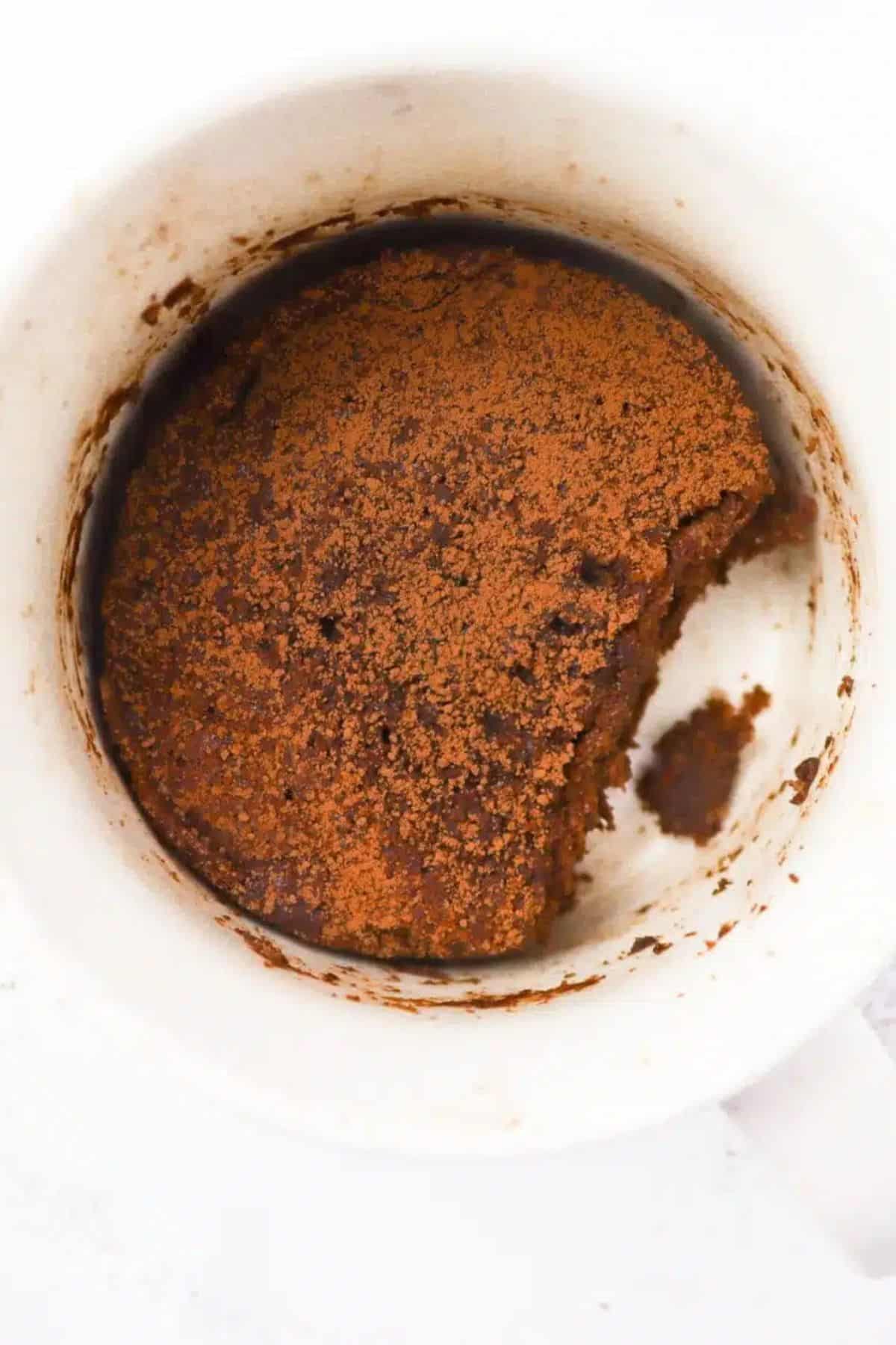 Close-up overhead view of a baked flaxseed muffin in a white ramekin, showing a dark golden-brown crumbly top