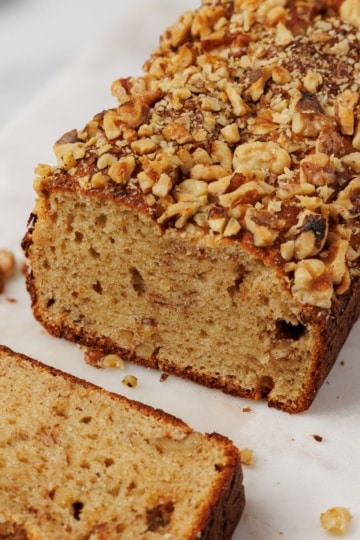 Close-up of a sliced gluten free banana bread loaf on a board, showing the cut end and soft crumb texture.