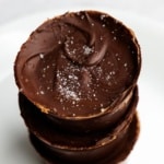 Stack of three keto big peanut butter cups topped with sea salt crystals.