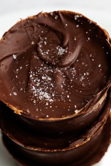 Stack of three keto big peanut butter cups topped with sea salt crystals.