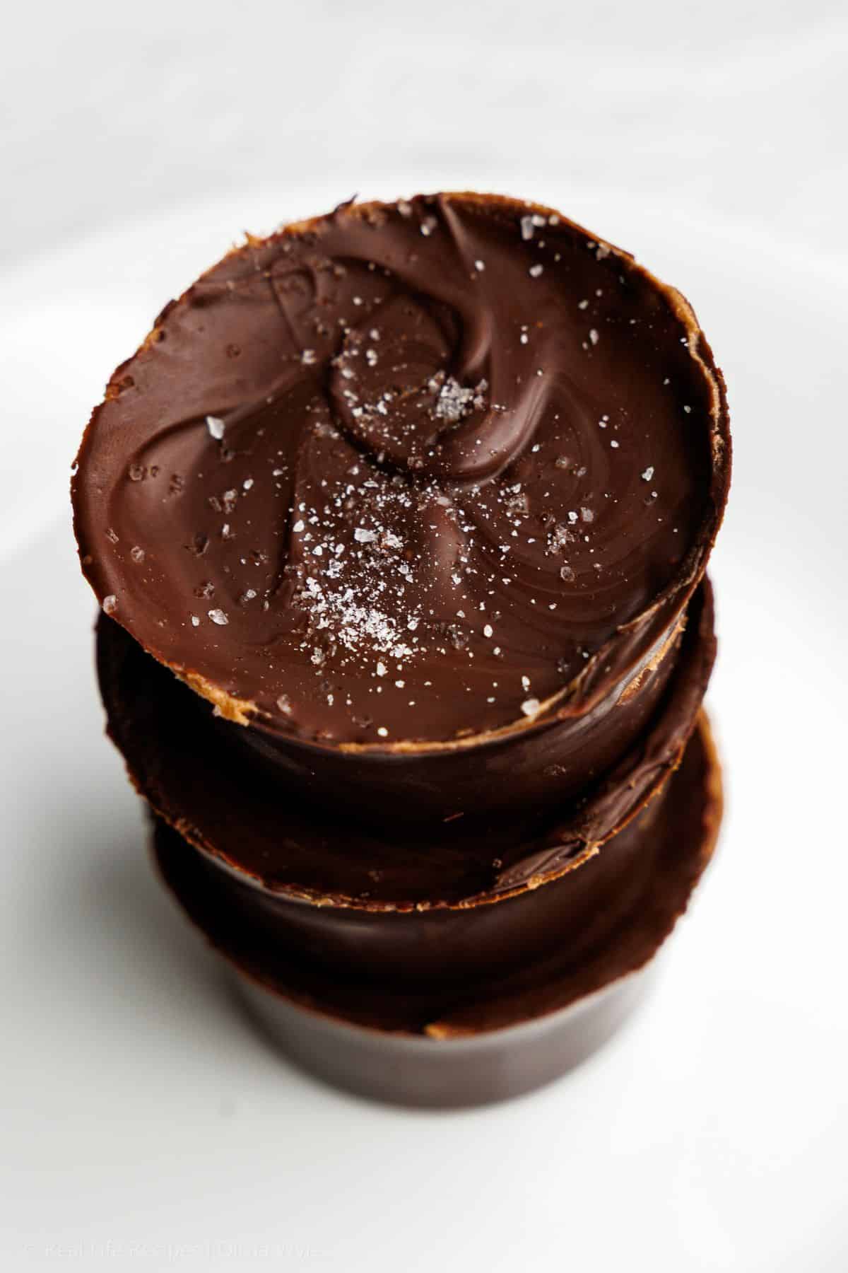 Keto big peanut butter cups with one broken open showing thick peanut filling inside