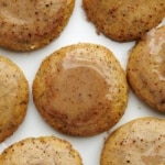 Overhead view of golden-brown chai latte cookies with visible chai tea specks arranged on white background.