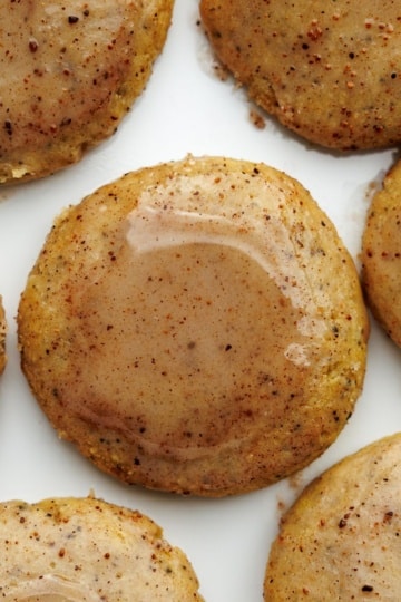 Overhead view of golden-brown chai latte cookies with visible chai tea specks arranged on white background.