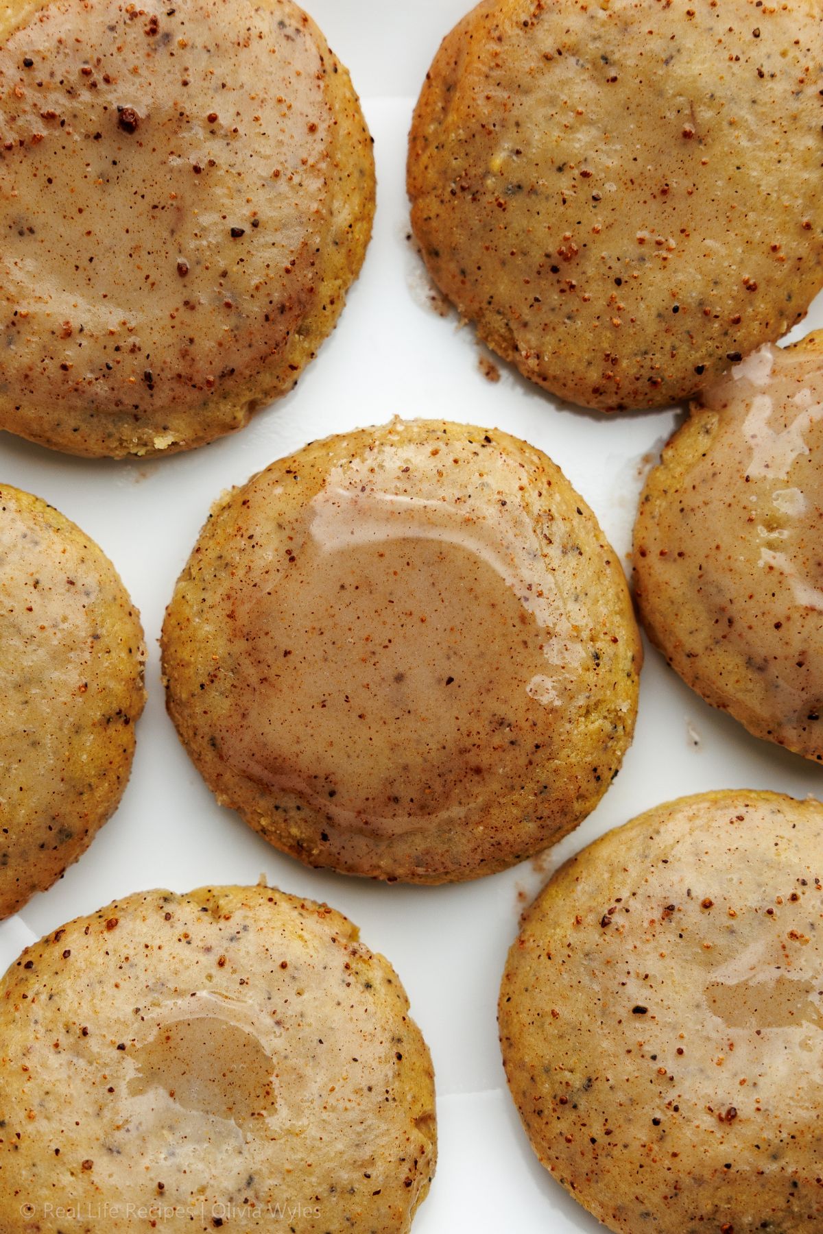 Overhead view of six golden protein chai latte cookies on a white background.
