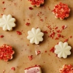 low-carb strawberry truffles showing plain white chocolate and freeze dried strawberry coated versions on parchment paper with scattered crumbs.