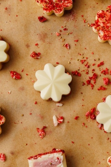 low-carb strawberry truffles showing plain white chocolate and freeze dried strawberry coated versions on parchment paper with scattered crumbs.
