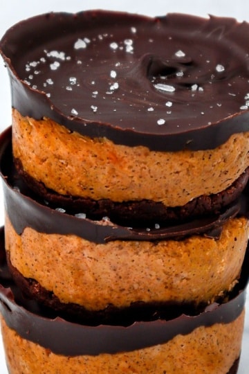 A stack of mini pumpkin chocolate cheesecakes topped with dark chocolate and a sprinkle of sea salt.
