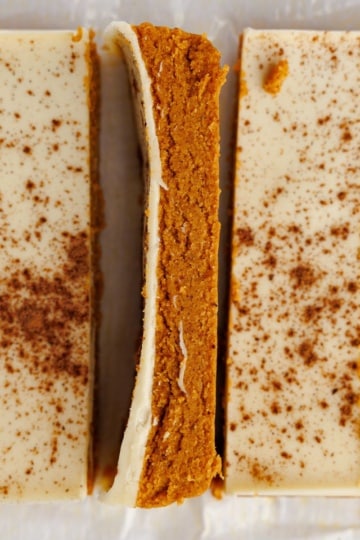 Close-up square crop of sliced pumpkin protein bars, one turned to reveal the pumpkin interior