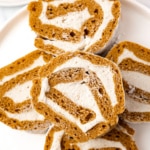 Sliced gluten-free sugar-free pumpkin roll on a white plate showing the cream cheese swirl inside.