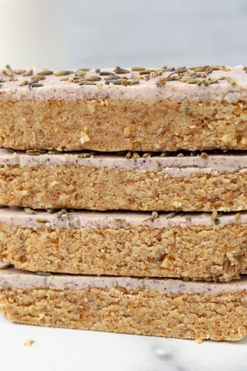 Close stack of four sliced lavender honey protein bars with dried lavender buds pressed into the glaze.