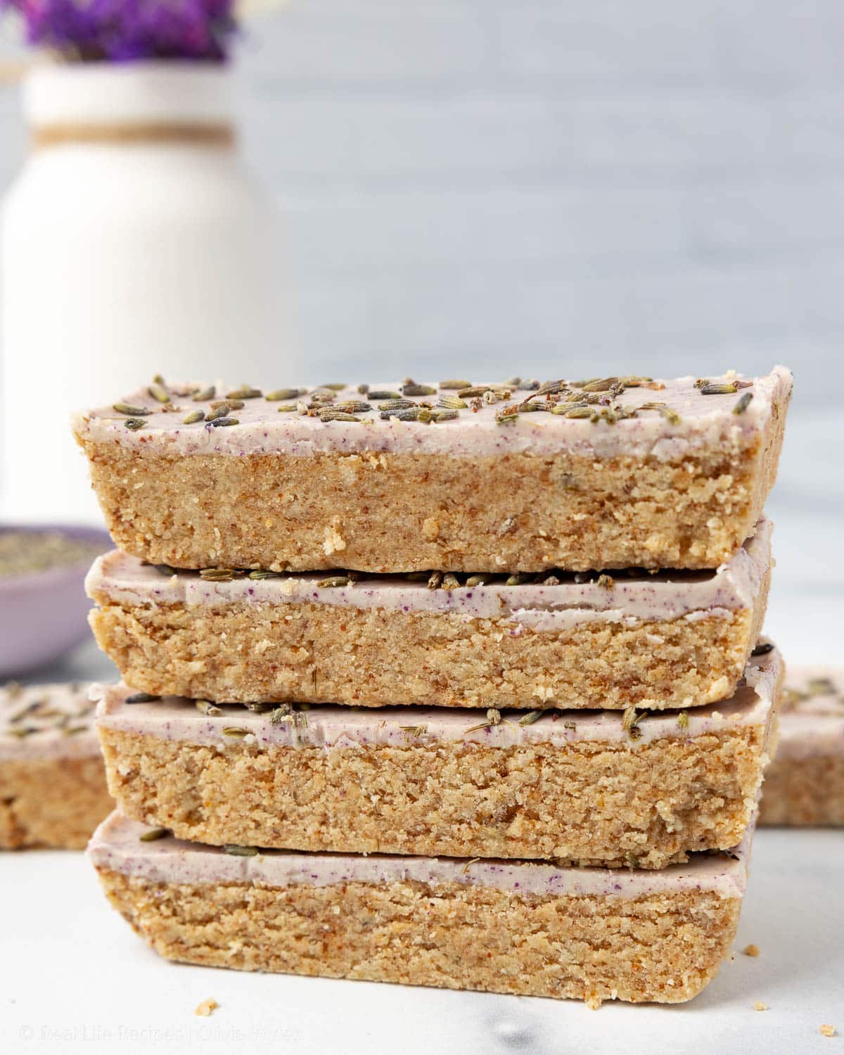 Stack of four honey lavender protein bars showing the crumbly base and pink glazed lavender top layer.