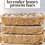 Stack of four honey lavender protein bars with pink glaze and dried lavender on top.