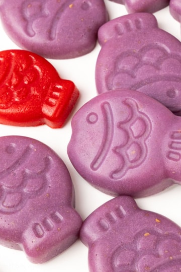 Close-up of Sugar-Free Gummy Fish showing fish scale detail, purple gummies beside one red fish gummy