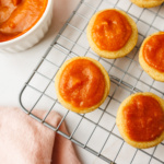 Baked peach cookies topped with glossy peach butter, cooling on a wire rack.