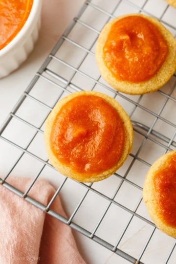 Baked peach cookies topped with glossy peach butter, cooling on a wire rack.