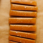 sliced apple caramel candy sprinkled with sea salt on brown parchment paper overhead view