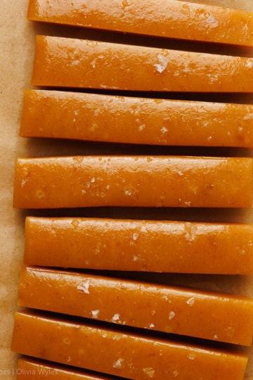 sliced apple caramel candy sprinkled with sea salt on brown parchment paper overhead view